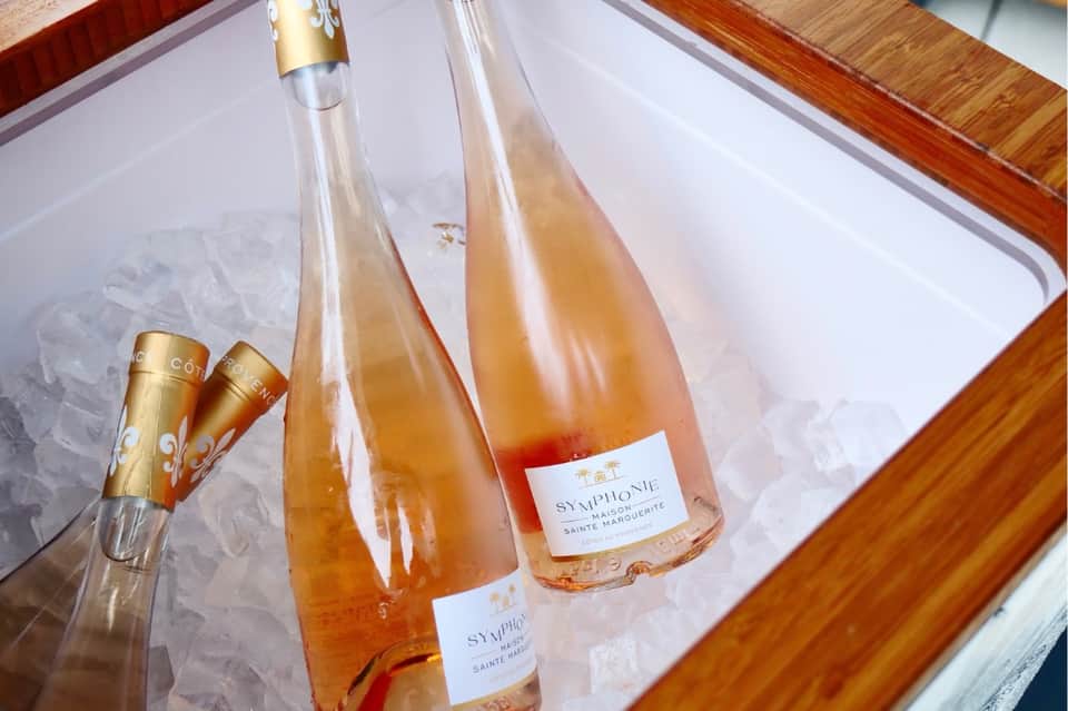 Champagne bottles chilling in ice bucket with gold flutes on wooden surface