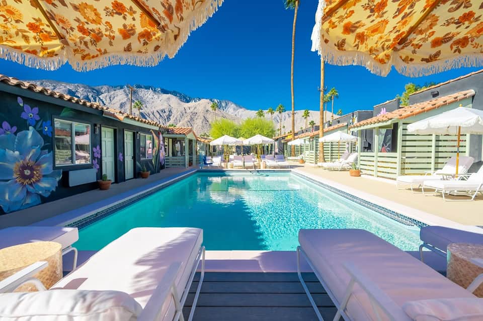 Resort pool with turquoise water, lounge chairs, and mountain backdrop on sunny day