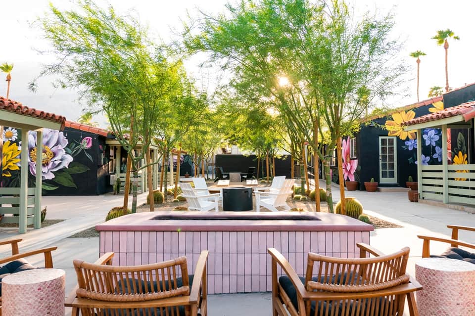 Colorful courtyard with painted flower murals, pink fire pit, and mature trees