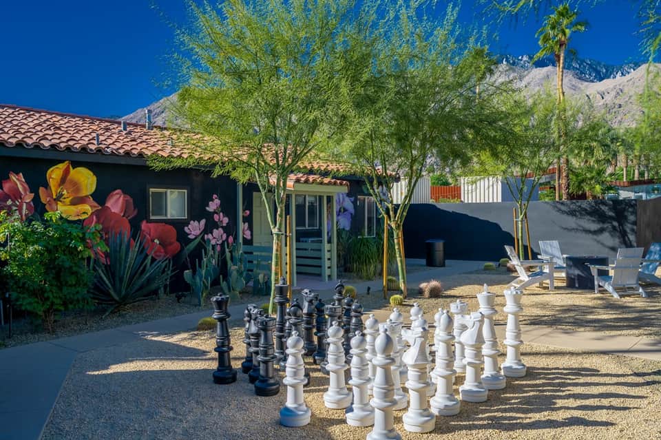 Colorful desert resort bungalow with vibrant flower mural, patio seating, and mountain backdrop