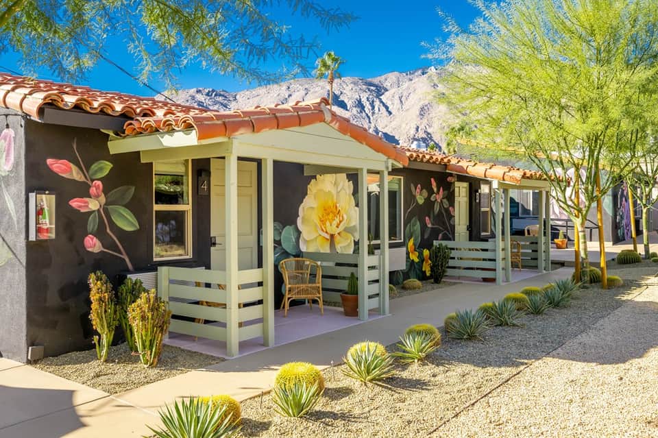 Colorful mid-century resort cottages with painted flower murals and mountains in background at desert location
