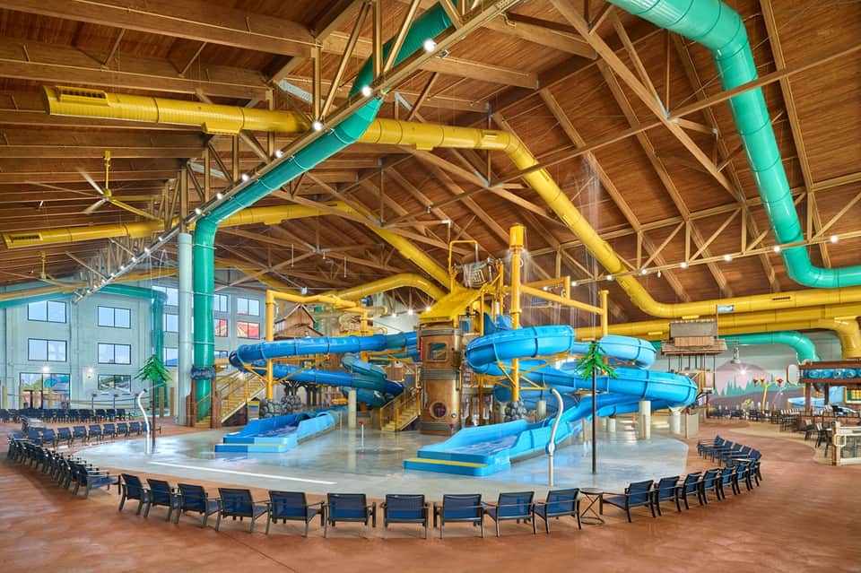 Indoor water park facility with colorful slide structures and wooden beam ceiling