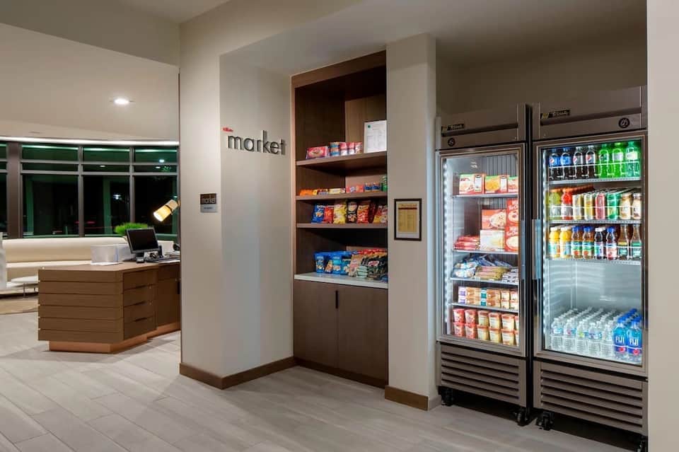Hotel market area with checkout desk, shelving, snack displays, and refrigerated beverage coolers
