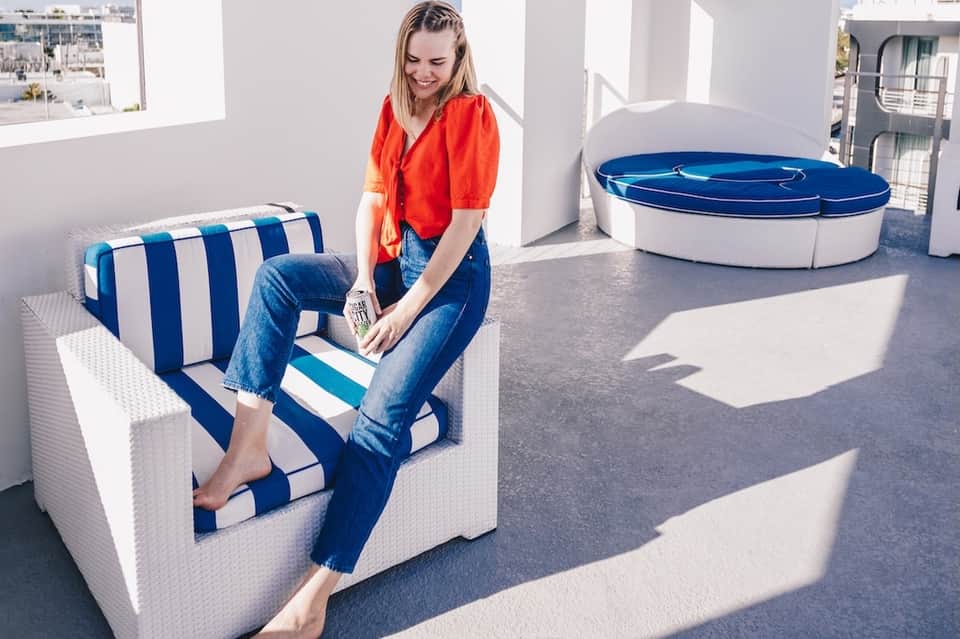 Woman in red shirt sitting on blue and white striped lounge chair on resort rooftop
