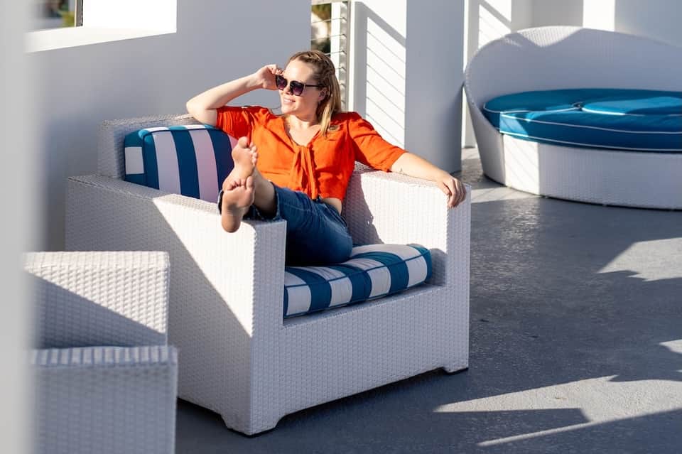 Woman relaxing in white wicker chair on sunny resort deck with blue accents