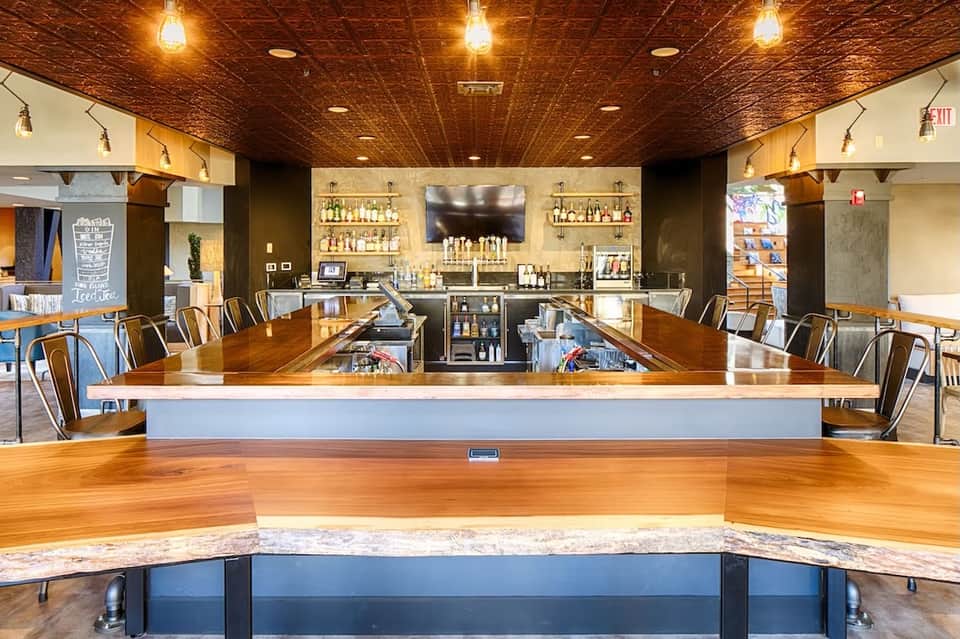 Modern hotel bar and lounge with wooden ceiling, marble counters, and shelving