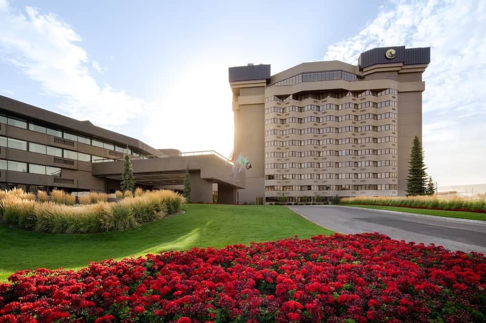 Modern hotel exterior with beige building, manicured red flower beds, and professional landscaping