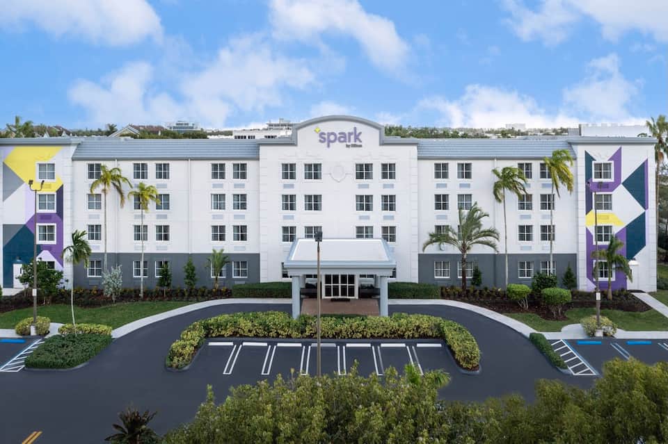 Modern Spark hotel exterior with colorful geometric design, palm trees, and parking lot