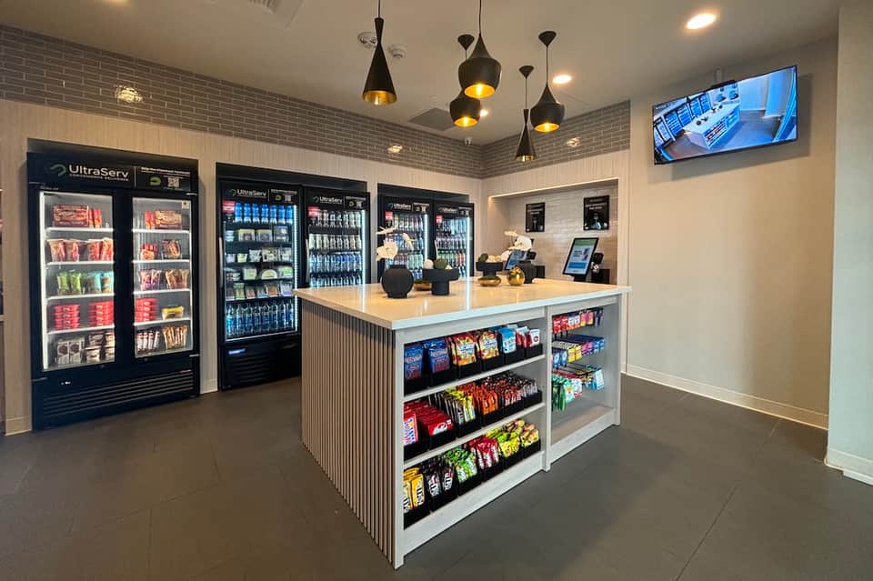 Modern convenience market with vending machines, counter service desk, and hanging black pendant lights