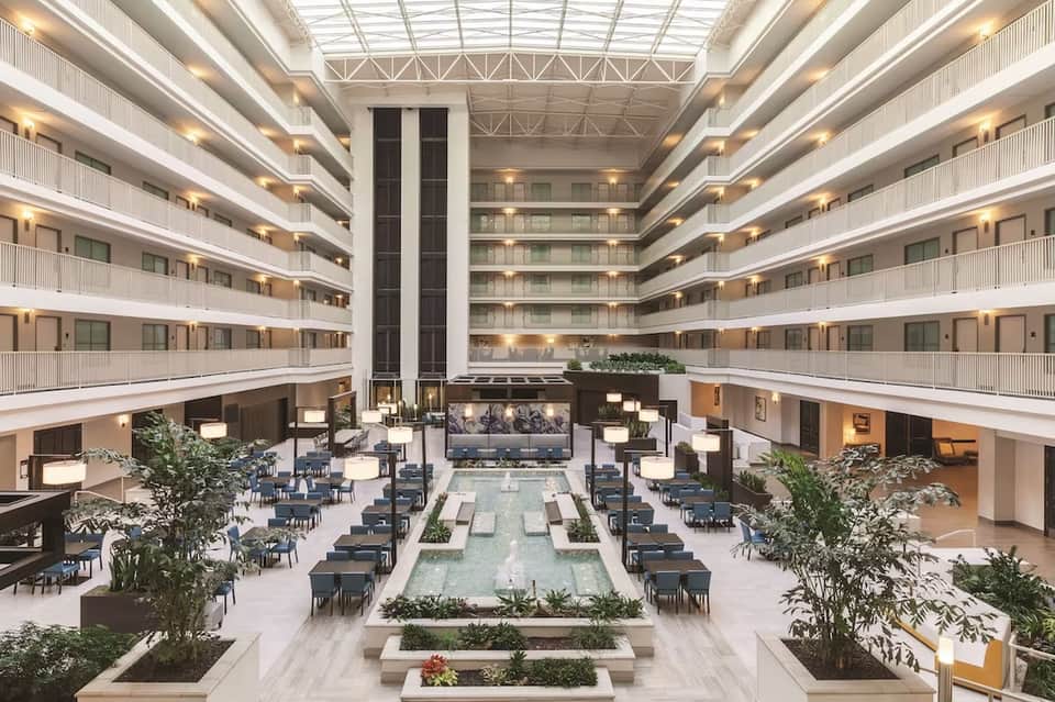 Modern hotel atrium lobby with multiple floors, central water feature, and contemporary furnishings