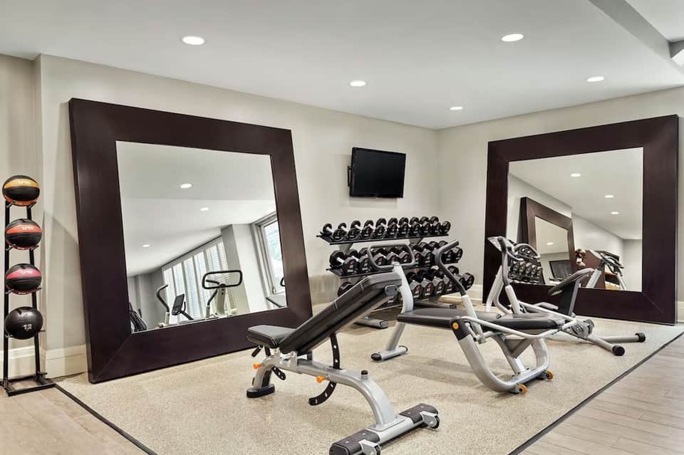 Fitness center with cardio equipment, free weights, mirrored walls, and flat screen TV