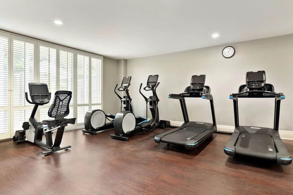 Modern fitness center with treadmills, ellipticals, stationary bikes, and bright natural lighting