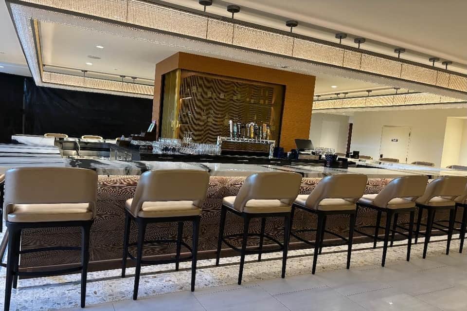 Hotel bar with cream leather seating, wooden accent wall, and ambient lighting