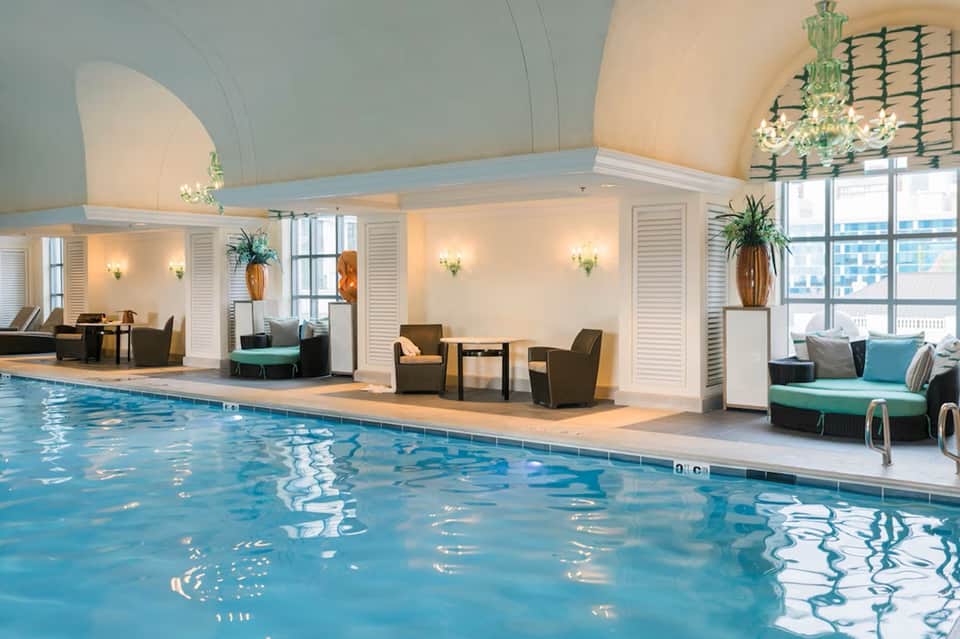 Indoor pool facility with arched ceiling, lounge seating, and natural lighting from windows