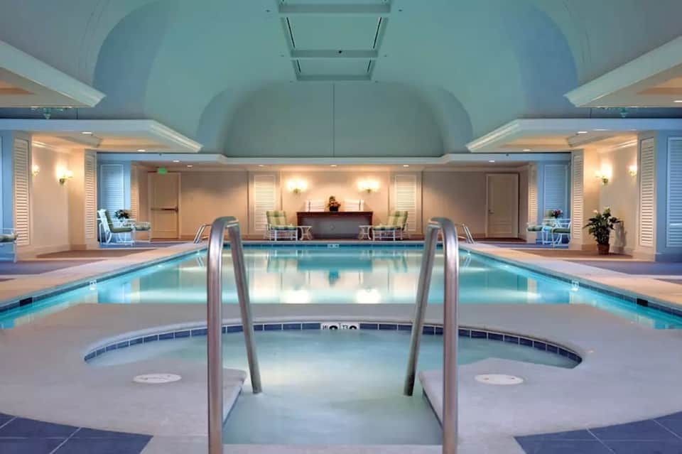 Indoor pool facility with arched ceiling, spa hot tub, and elegant architectural design