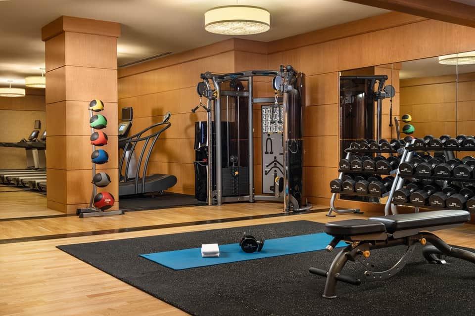 Modern fitness center with wood walls, exercise equipment, weights, and mirrors