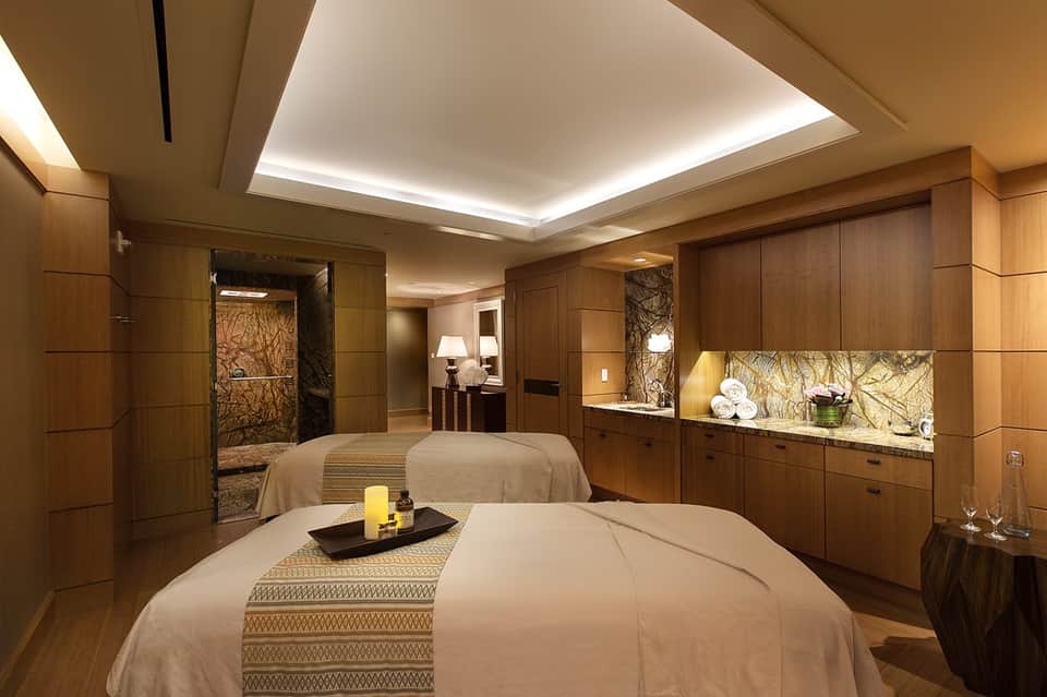 Luxury spa treatment room with massage beds, wood paneling, and ambient lighting