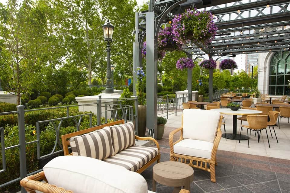 Outdoor terrace with purple hanging flowers, wooden furniture, and garden views