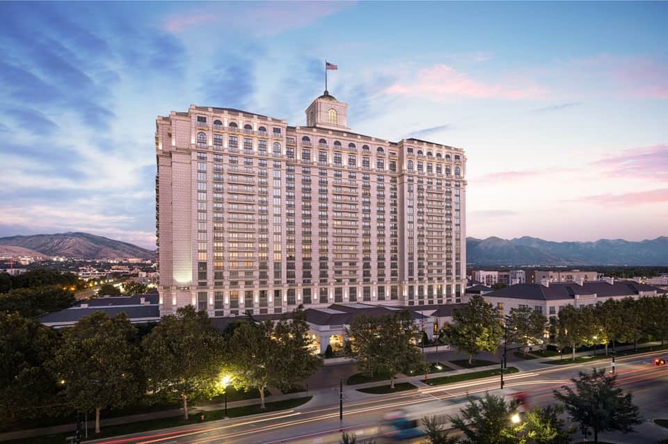 Grand pink hotel tower at dusk with illuminated landscape and mountain backdrop
