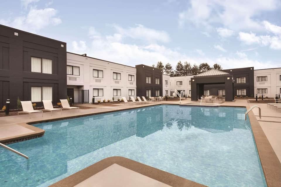 Modern apartment complex pool with lounge chairs, dark and light-colored buildings