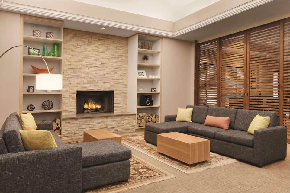 Contemporary living room with fireplace, built-in shelving, gray seating, and wood accents