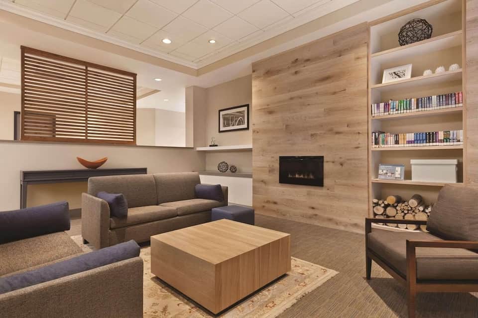 Contemporary hotel lounge with fireplace, built-in shelving, seating area, and wood accents