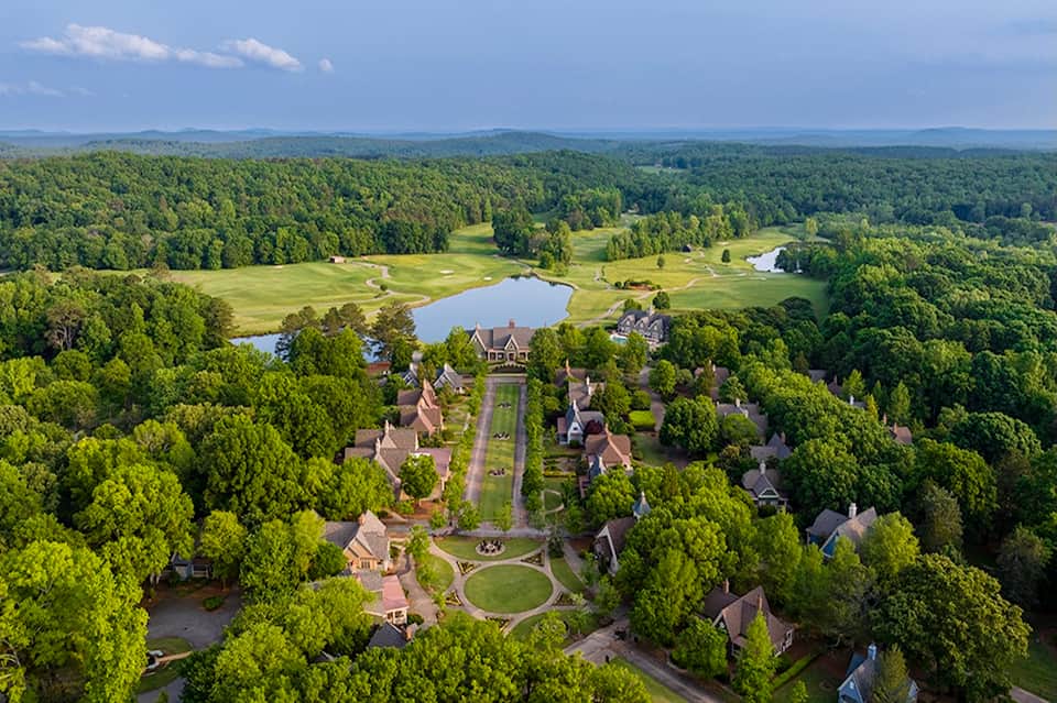 Aerial view of luxury resort community with manicured lawns, ponds, and tree-lined streets