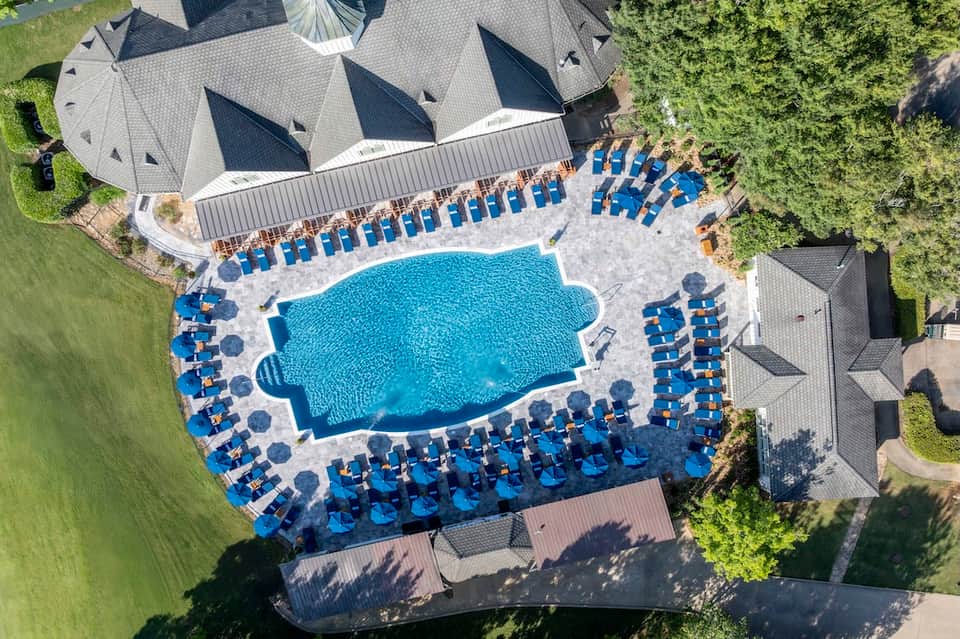 Aerial view of resort pool surrounded by blue lounge chairs and manicured grounds