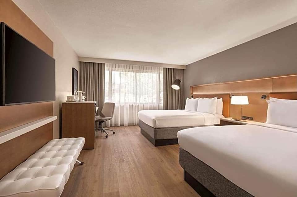 Modern hotel room with two queen beds, wood accents, and contemporary furnishings