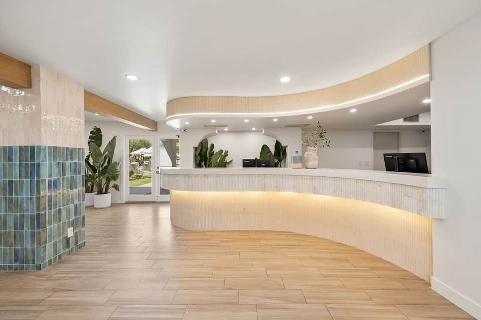 Modern hotel lobby with curved reception desk, white design, and blue tile accent wall