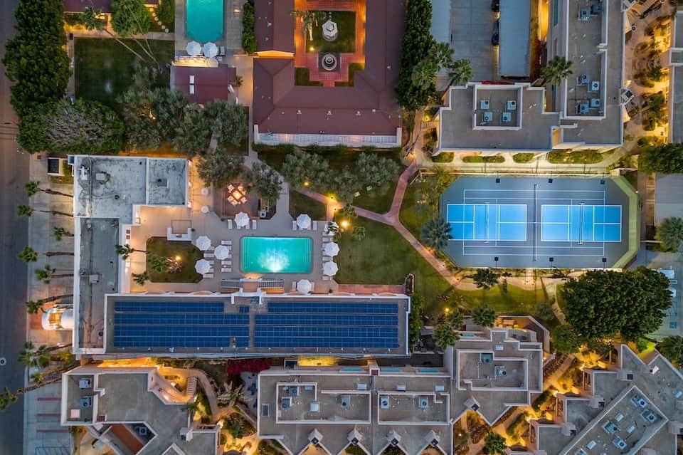 Aerial view of resort grounds showing multiple pools, tennis courts, and landscaping at dusk