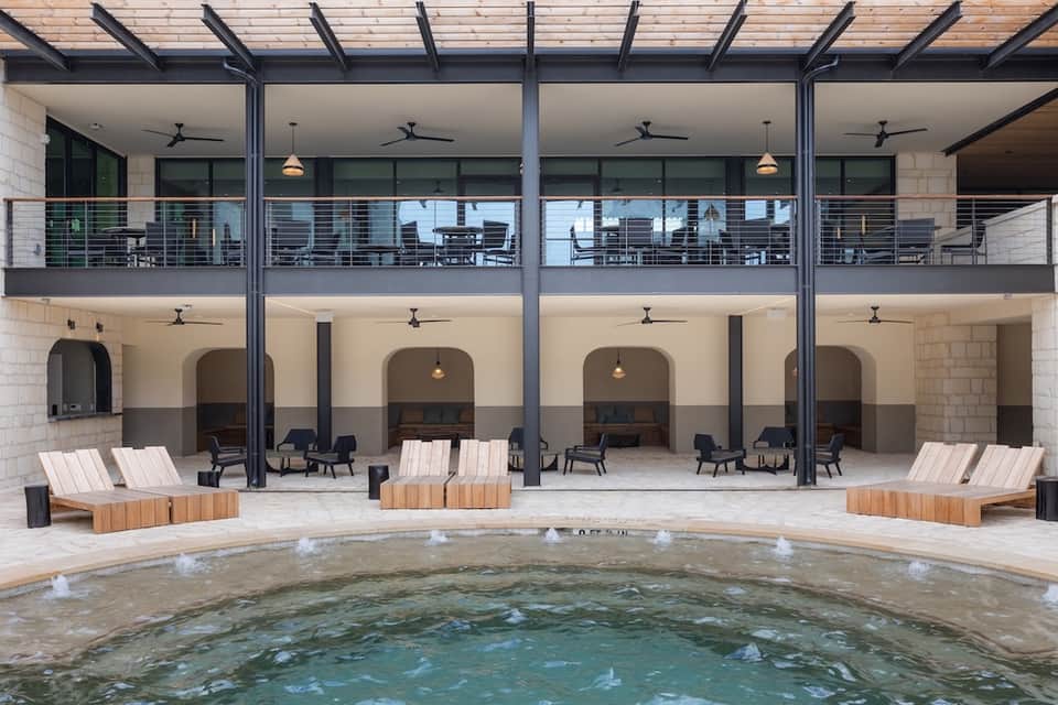 Multi-story courtyard with modern architecture, lounge seating, and small indoor pool