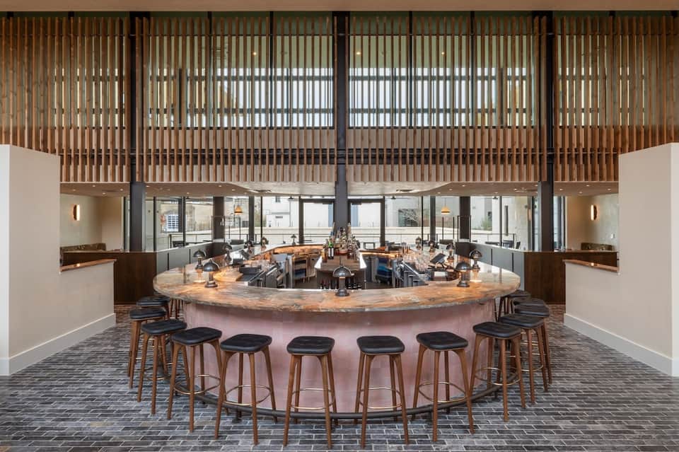 Modern circular bar with wooden counter, tall seating, and decorative wood slat ceiling design