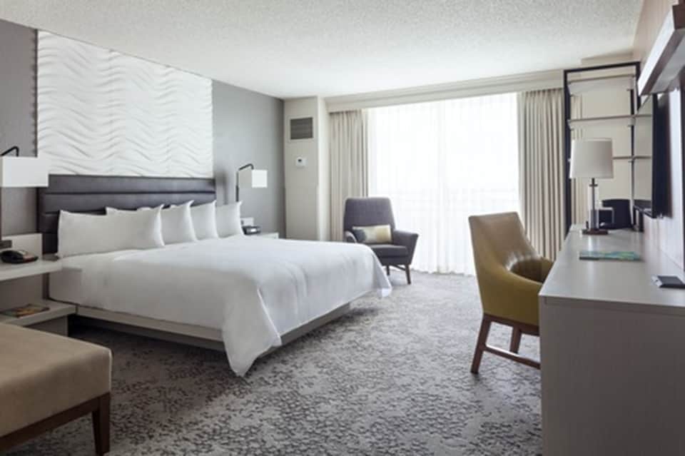 Modern hotel bedroom with king bed, contemporary furnishings, and balcony view