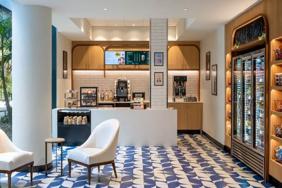 Contemporary café interior with white subway tile, wood accents, and refrigerated beverage cases