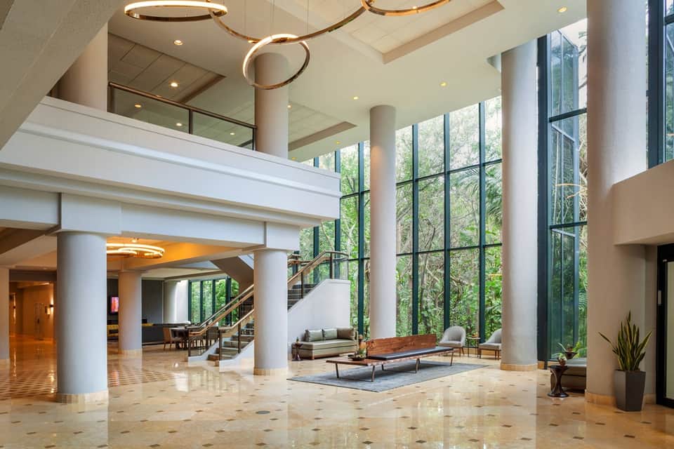 Luxury hotel lobby with soaring ceiling, modern sculptural chandelier, and minimalist seating