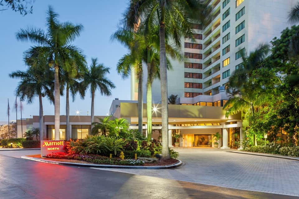 Marriott North hotel entrance at dusk with palm trees, illuminated entrance, and multi-story building