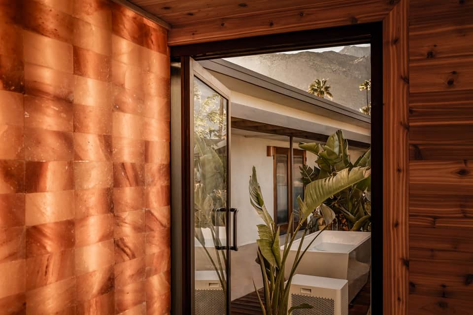 Wooden entrance to spa with copper metallic door and mountain view through glass