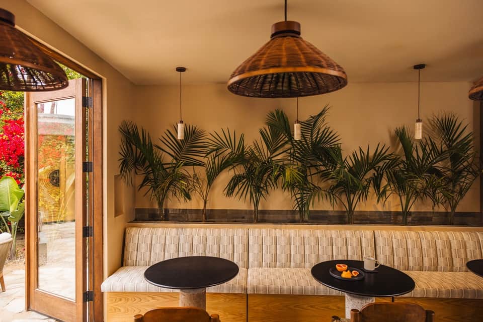 Casual dining area with woven pendant lights, palm plants, and open terrace access