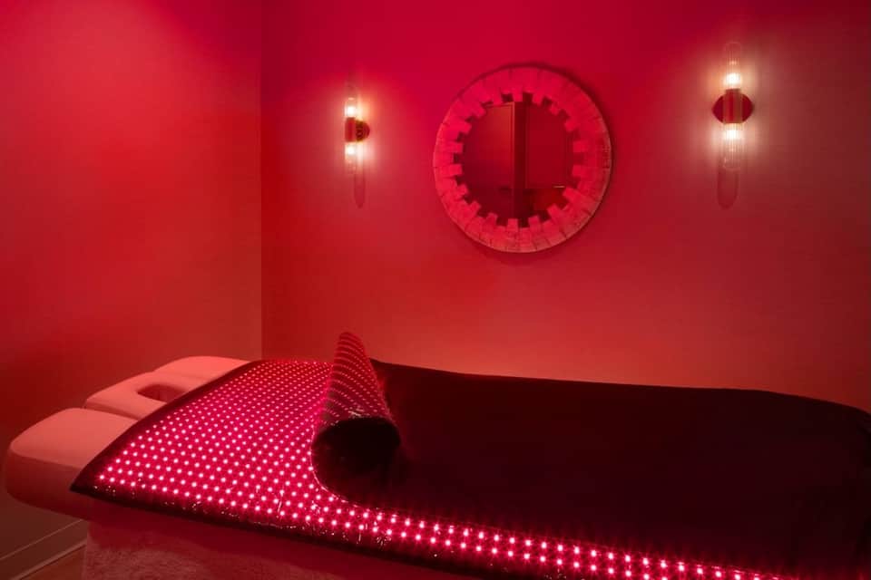 Modern red illuminated spa or wellness room with curved seating and artistic neon lighting