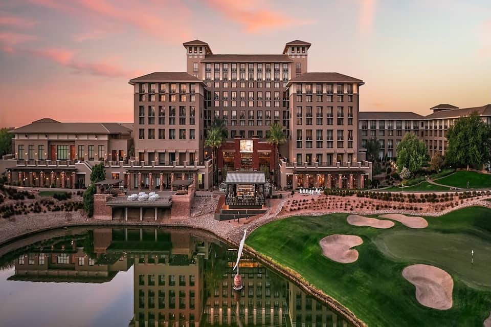 Luxury resort complex at sunset with golf course, water features, and grand architecture
