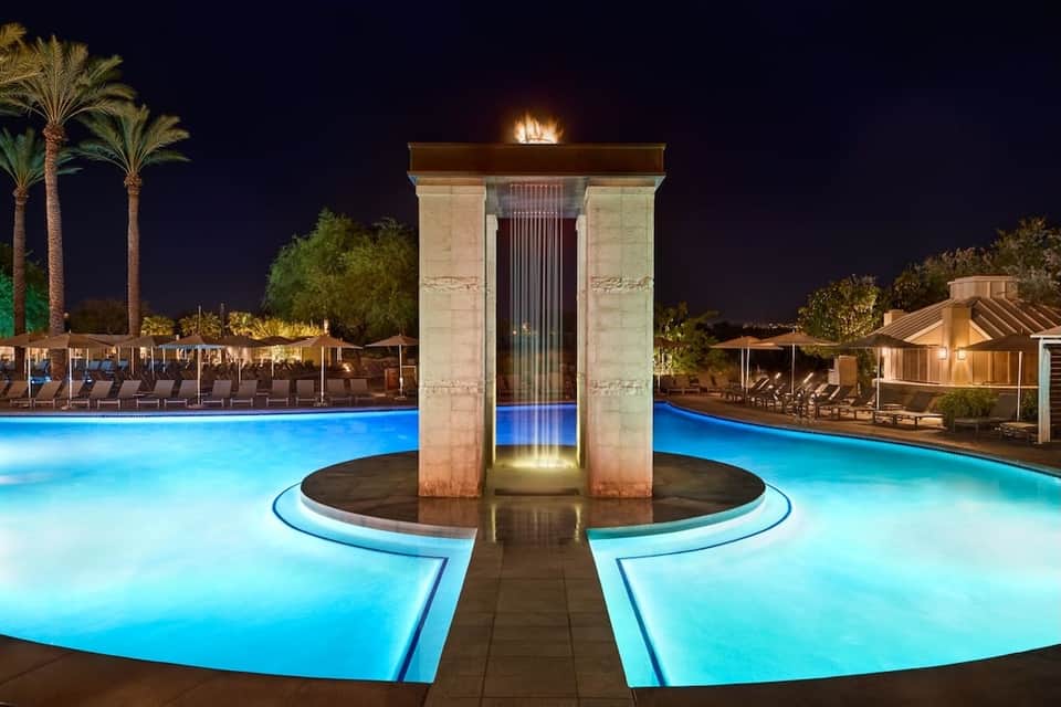 Stunning nighttime resort pool with geometric water feature and columns, lit in vibrant blue
