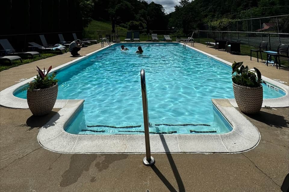 Olympic-style outdoor pool with blue water, lounge chairs, and landscaped grounds