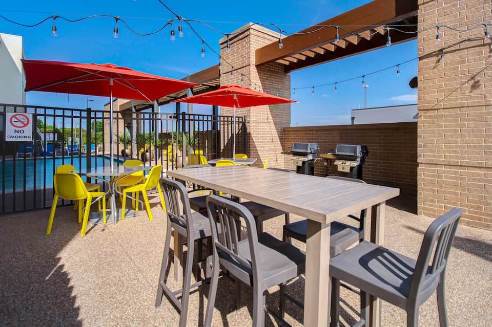 Rooftop terrace with red umbrellas, dining tables, and pool access