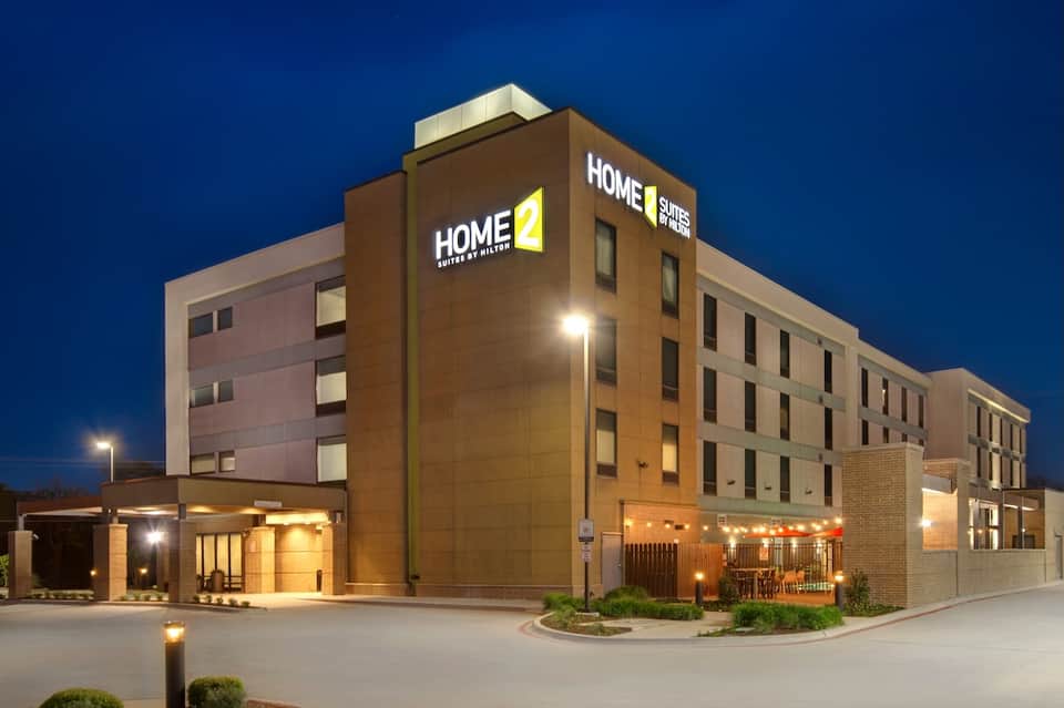 Home2 Suites hotel exterior at dusk with illuminated brick facade and modern architecture