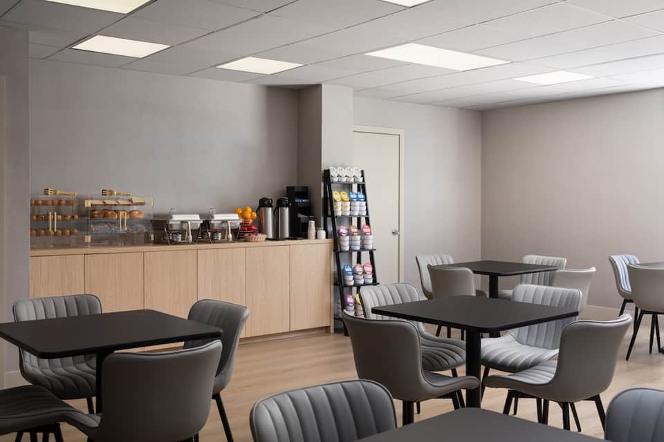 Bright spa lounge with wooden cabinetry, black tables, gray upholstered chairs, and product displays