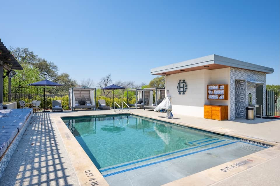 Resort swimming pool with modern cabanas, lounge chairs, and pool house facility