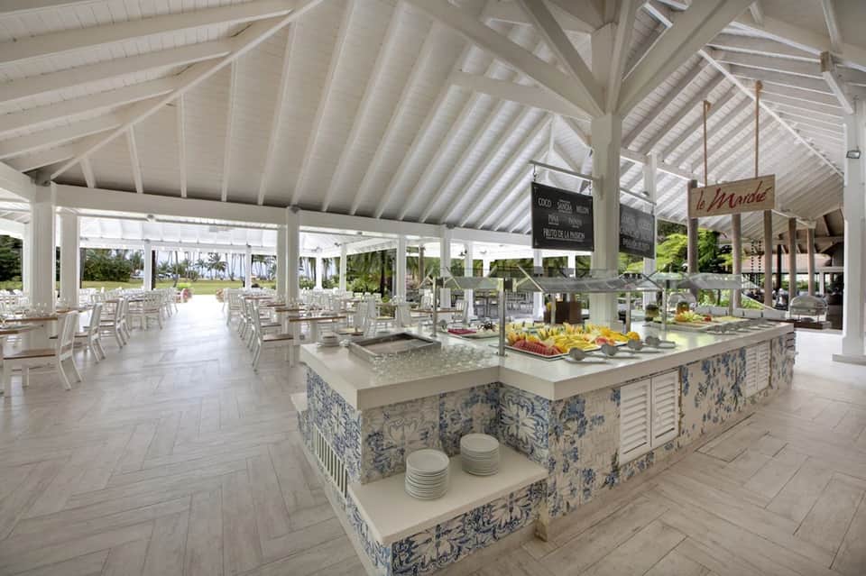 Elegant white dining pavilion with herringbone floors, blue patterned serving station, tables, and hanging signage