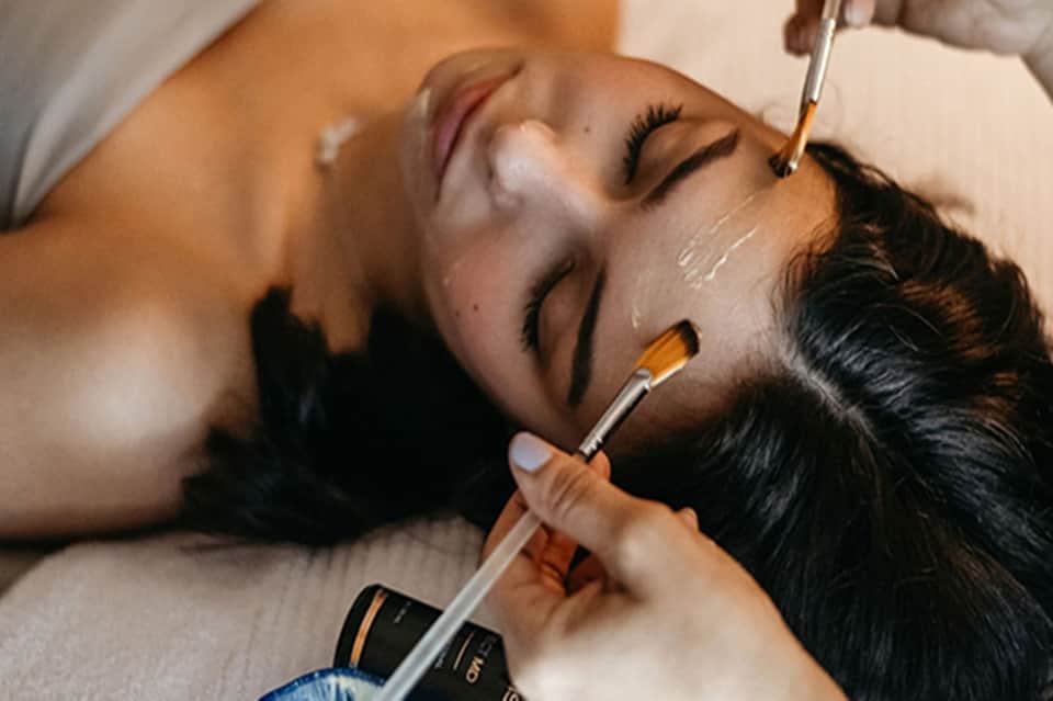 Spa treatment close-up showing facial mask application with brush on relaxing client
