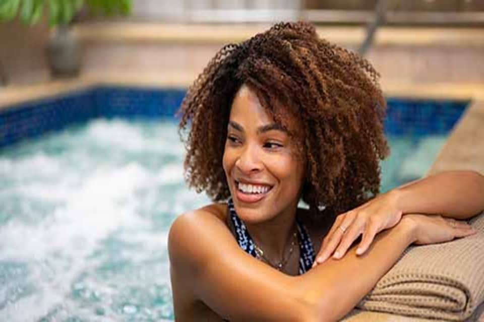 Woman enjoying a resort pool with turquoise water and palm trees in background